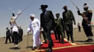 South Sudanese President Salva Kiir, center, walks with Sudanese counterpart Omar al-Bashir, Khartoum, Oct. 2011 (file photo).