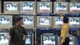 Indian salesman tunes televisions at an electronics shop as government official on screen pledges to boost spending for rural infrastructure, 2006 (file photo).