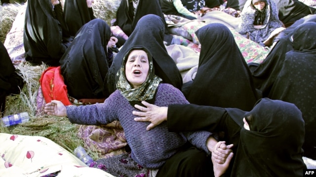  Iranians mourn over the covered bodies of loved ones in the village Baje-Baj, near the town of Varzaqan, who were killed in twin earthquakes that hit northwestern Iran, August 12, 2012.