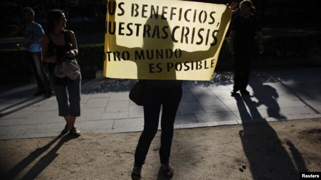 Una mujer en Madrid sostiene un letrero contra las medidas de austeridad en la Eurozona en el que se lee: “Sus beneficios, nuestras crisis. Otro mundo es posible” [Foto: Reuters] 