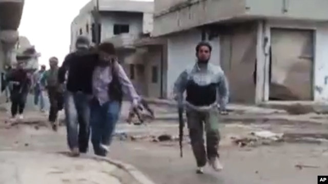 Image made from amateur video shows a Syrian rebel helping an injured man in Rastan, Homs, Syria.