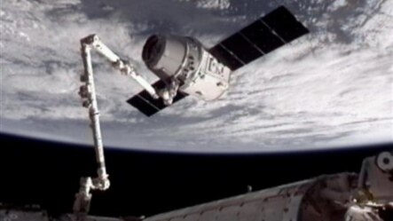 Foto yang dirilis oleh NASA-TV ini memperlihatkan Kapsul Dragon SpaceX (atas) saat ditangkap oleh tangan robot Canadarm2. Tangan robot ini merapatkan Kapsul Dragon ke Stasiun Antariksa Internasional (ISS), Jum'at (25/5).